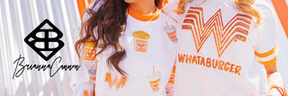 Two women standing in front of an orange-and-white striped Whataburger building wearing Brianna Cannon x Whataburger