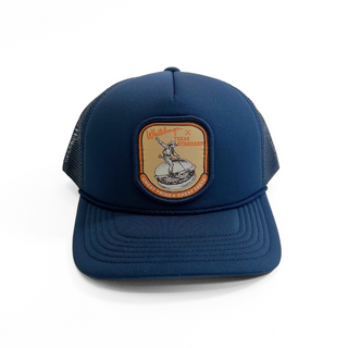Blue trucker cap with a patch featuring a graphic design on a white background