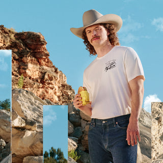 Man in a cowboy hat and white t-shirt standing in a desert landscape