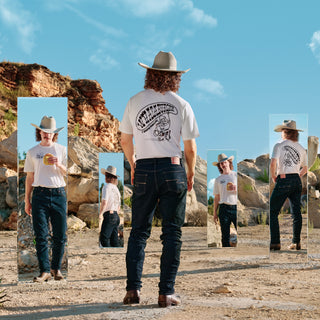Person wearing a cowboy hat and white t-shirt with graphic design, standing in a desert landscape.
