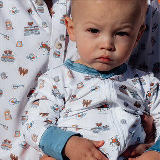 Close-up of baby in Whataburger onesie with Texas-themed icons and blue trim.