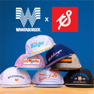 Stack of colorful Whataburger-themed Staunch Outfitters brand hats on a wooden table. Whataburger and Staunch logos on a bold blue background.