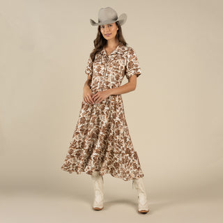 Woman wearing a floral dress and cowboy hat on a beige background