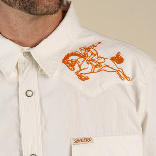 White shirt with orange embroidered design on a beige background