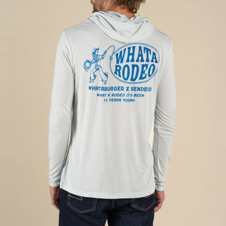 Person wearing a gray hoodie with 'Whata Rodeo' branding on the back against a beige background