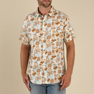 Man wearing a patterned shirt with Cowboy-themed design on a beige background