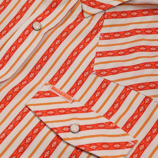 Close-up of a orange and white striped shirt with floral patterns, featuring the brand logo