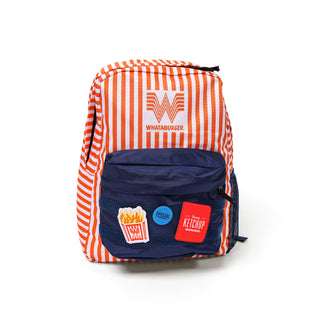 A Whataburger Striped Patch Backpack featuring bright orange and white vertical stripes, the iconic "W" Whataburger logo, and a navy-blue front pocket with fun patches, including fries, a blue "Special" day dot, and a red "Fancy Ketchup" square patch.