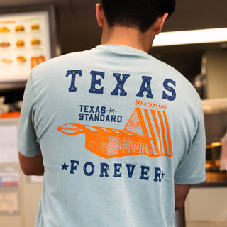 Person wearing a light blue t-shirt with 'Texas Forever' design in a casual setting