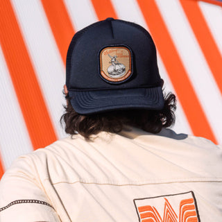 Person wearing a navy blue cap with a logo against a striped background