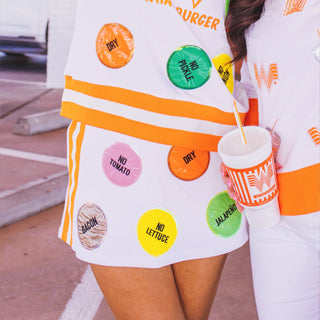 Person wearing a Brianna Cannon x Whataburger skort with Day Dot pattern and holding a cup outdoors.