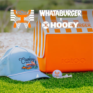 Golf hat, ball, and cooler with Whataburger and Hooey branding on grass.