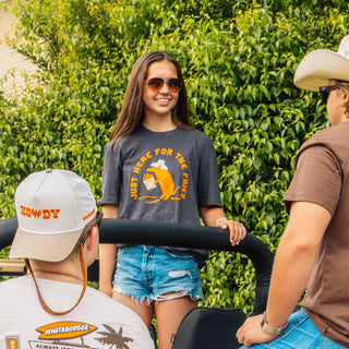 Woman standing on back of truck wearing Fry Dillo Shirt in front of leafy wall