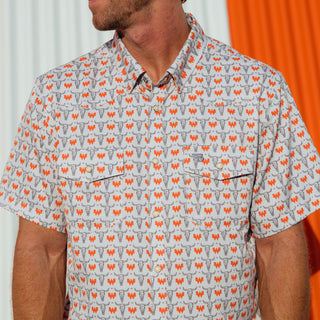 A man wearing a short-sleeve button-up shirt with a cow skull and Whataburger logo pattern in orange and gray on a white background.