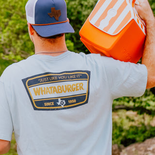 Person wearing a 'Whataburger' t-shirt holding an orange cooler outdoors.
