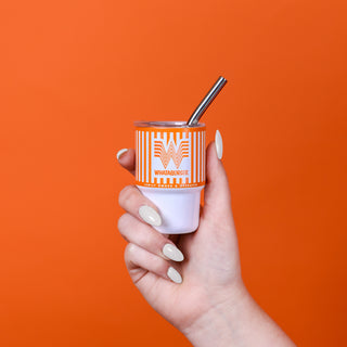 Hand holding Mini Whataburger Tumbler against orange background