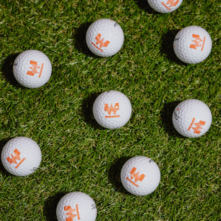 View Titleist Velocity Golf Balls with Whataburger Logo sitting on the grass